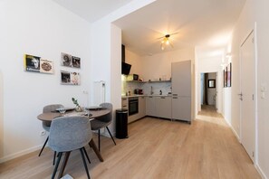 Una cocina moderna con comedor, ventilador de techo y un pasillo que conduce a un dormitorio.