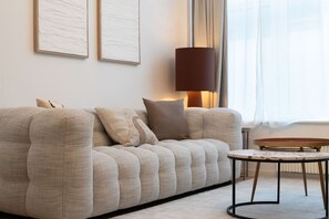 A modern living room with a sofa, a round coffee table, a floor lamp, and artwork on the wall. - Modern Cocoon - Gare du Midi - BRO144.00 (Anderlecht)