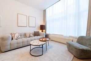 A modern living room with a sofa, two side tables, a lamp, and a radiator. - Modern Cocoon - Gare du Midi - BRO144.00 (Anderlecht)