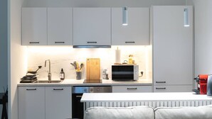 Una cuina moderna amb armaris blancs, forn integrat i taulell amb diversos utensilis de cuina.