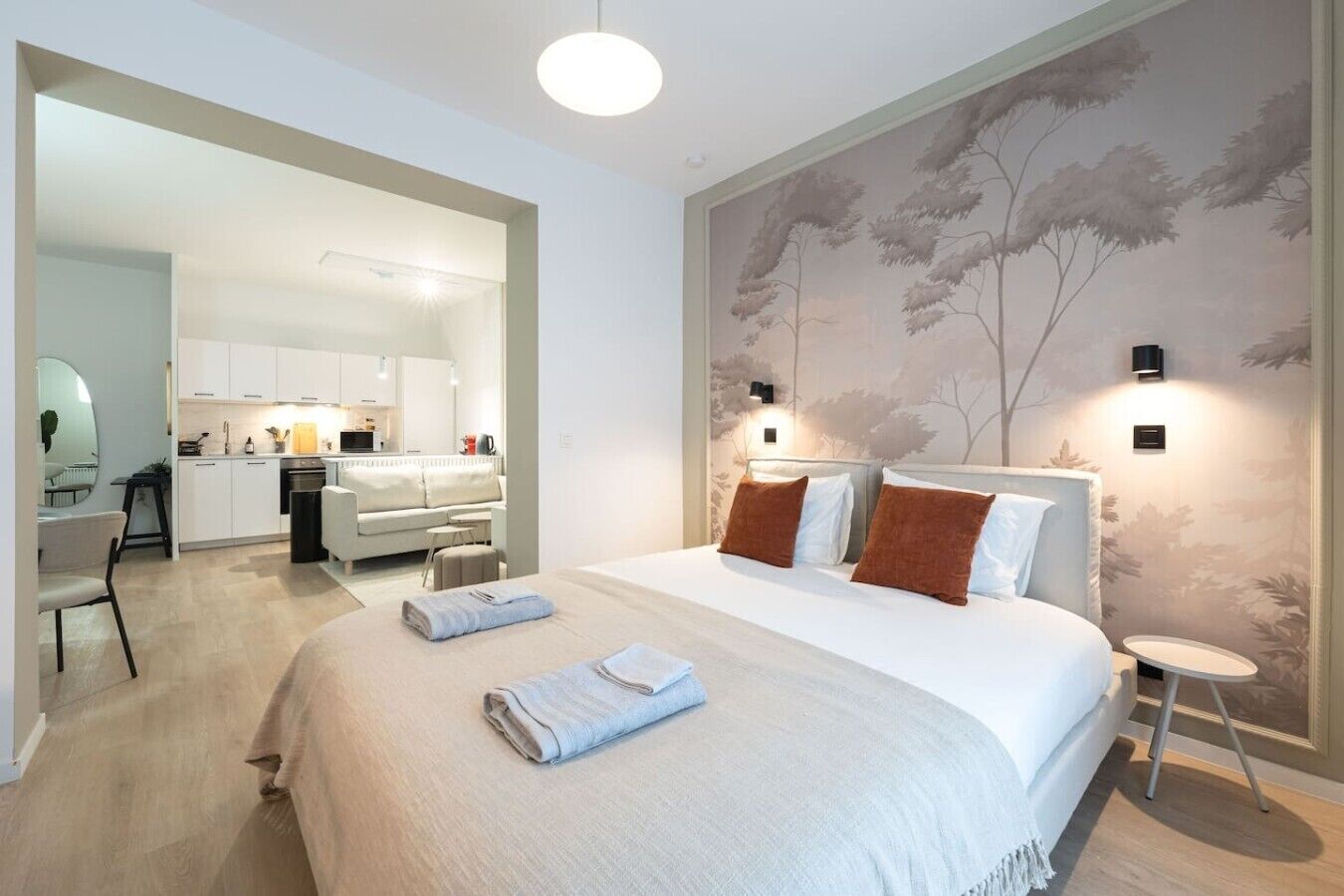 Moderni hotellihuone, jossa on suuri sänky, työpöytä ja pieni keittiönurkkaus.