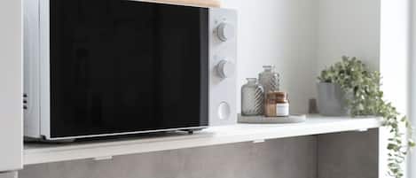 Un four à micro-ondes doté d’un dessus en bois, posé sur une étagère blanche.
