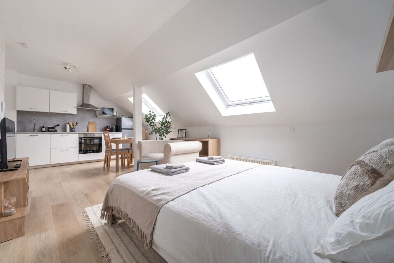 Een moderne slaapkamer met een groot bed, dakraam, kitchenette en een eethoek.