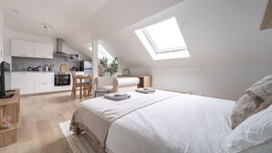 Un dormitorio moderno con una cama grande, tragaluces, kitchenette y comedor.