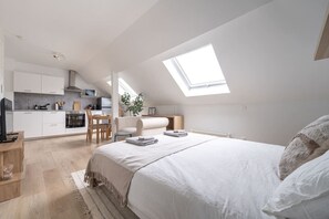 Ein modernes Schlafzimmer mit einem großen Bett, einem Oberlicht, einer Küchenzeile und einem Essbereich.