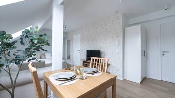 Un espace repas moderne avec une table en bois, des chaises et un téléviseur en arrière-plan.