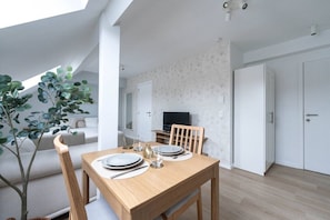 Un espace repas moderne avec une table en bois, des chaises et un téléviseur en arrière-plan.
