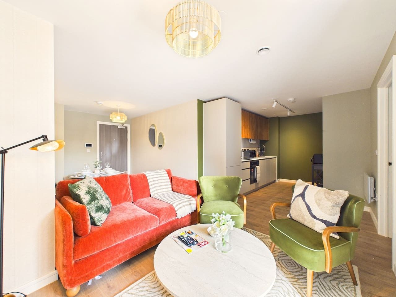 A modern living room with a red sofa, green armchairs, and a round coffee table.