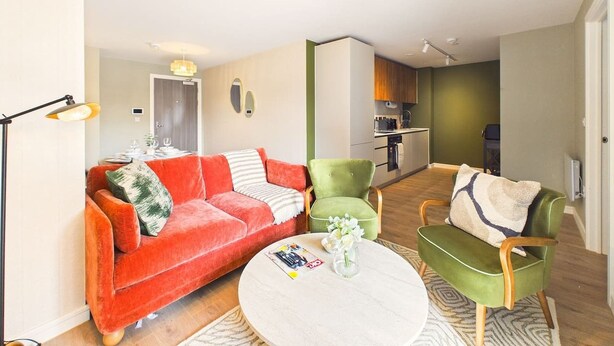 Un salon moderne avec un canapé rouge, des fauteuils verts et une table basse ronde.