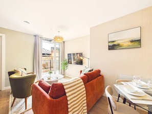 Una sala de estar moderna con un sofá, sillones y una mesa de comedor preparada para dos personas.