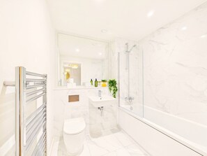 Un baño moderno con cabina de ducha de vidrio, un lavamanos blanco y un inodoro.