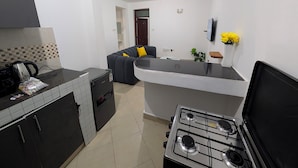 A compact kitchen with a gas stove, a refrigerator, and a dining area with a sofa. - Perfect apartment in Nairobi for a relaxing stay (Nairobi)