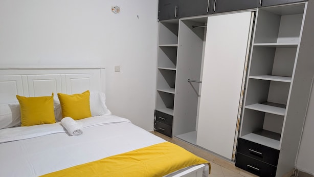 A bedroom with a bed, a wardrobe, and a small cabinet. - Perfect apartment in Nairobi for a relaxing stay (Nairobi)