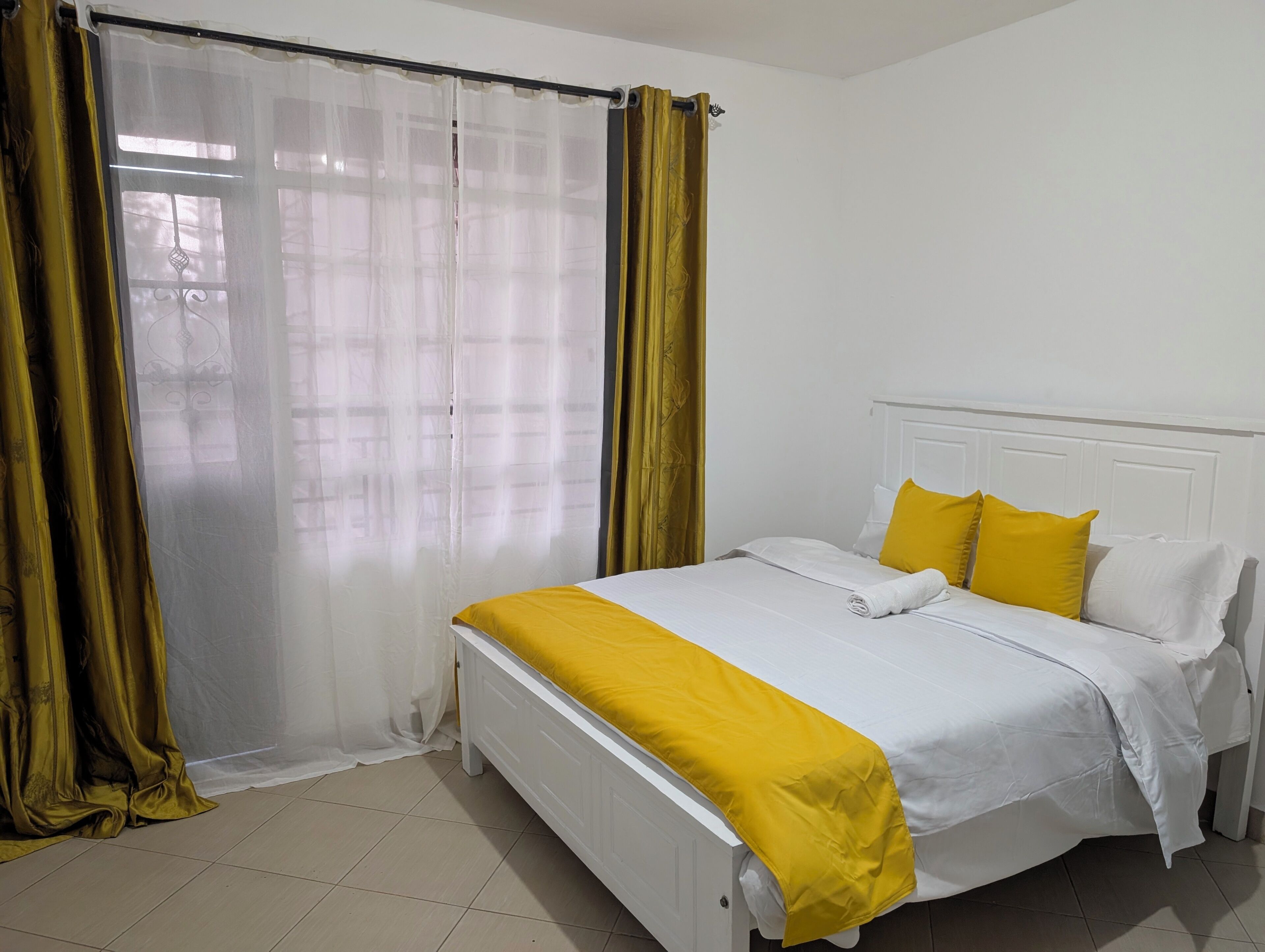 A hotel room with a bed, curtains, and a window.