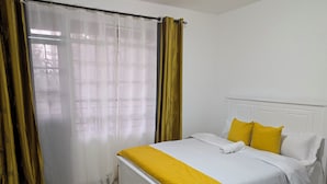A hotel room with a bed, curtains, and a window. - Perfect apartment in Nairobi for a relaxing stay (Nairobi)