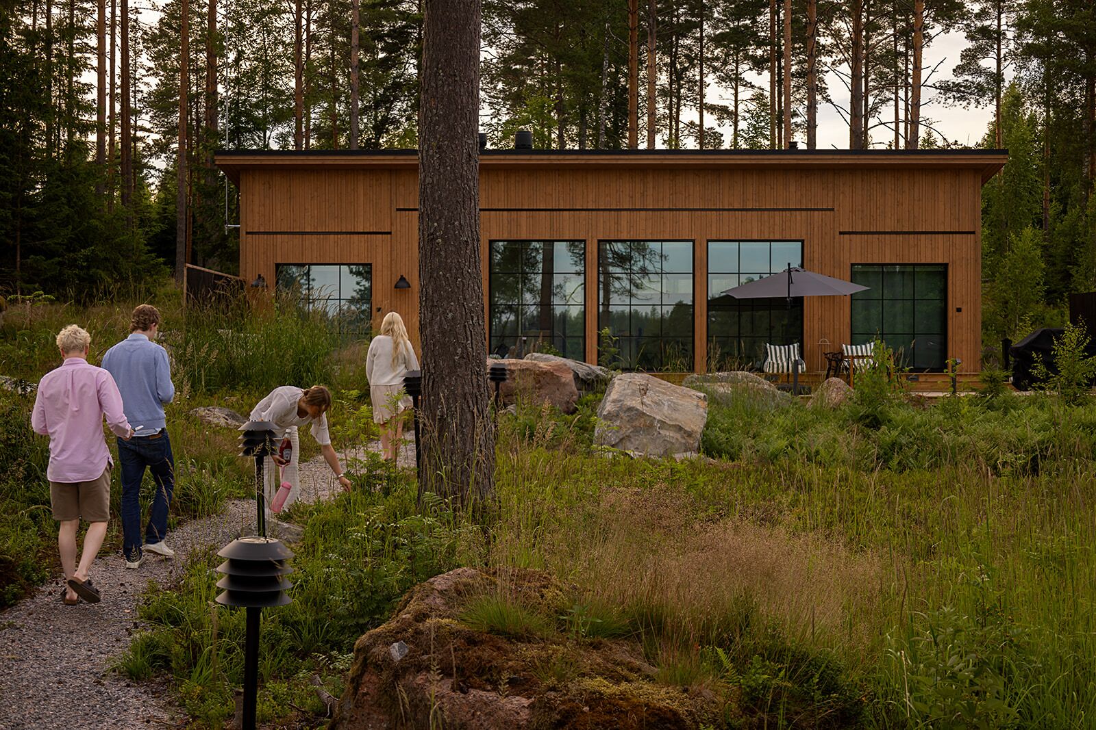 Un bâtiment moderne en bois, doté de grandes fenêtres et entouré d’un cadre naturel, à savoir une forêt.