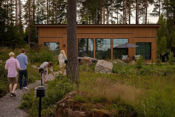 Un edificio moderno de madera con ventanas amplias, rodeado por un entorno forestal natural.