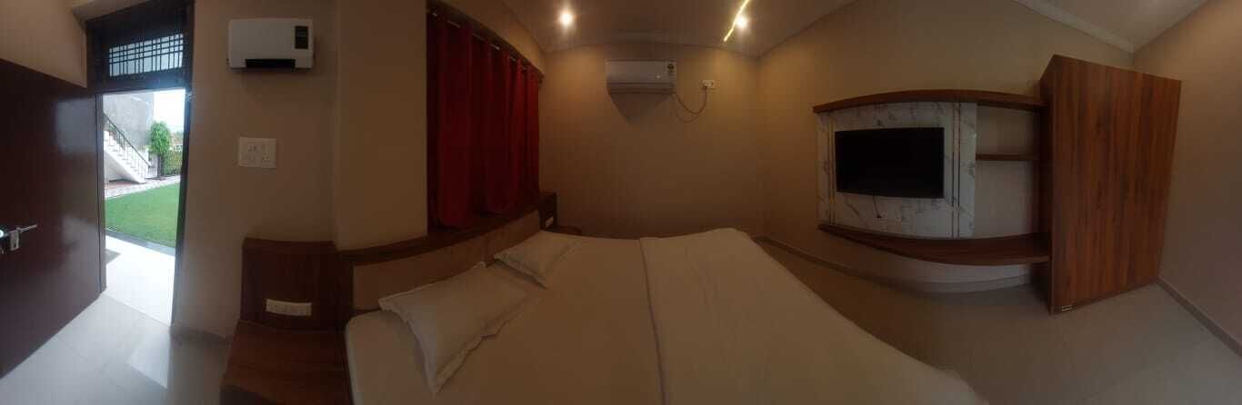 A bedroom with a bed, a TV, and a window with curtains.