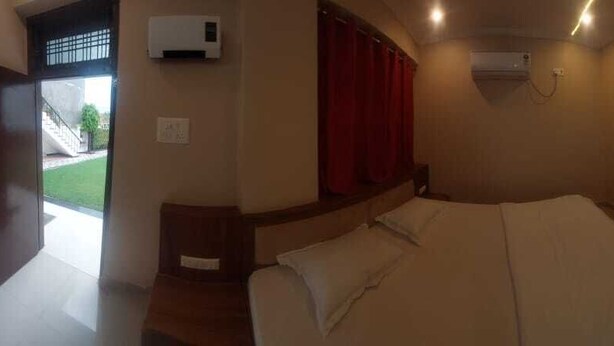 A bedroom with a bed, a TV, and a window with curtains. - Rangoli Garden Homestay (Varanasi)
