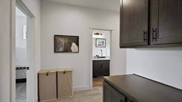 A hallway with a coat rack, a framed picture on the wall, and a dark wooden cabinet.