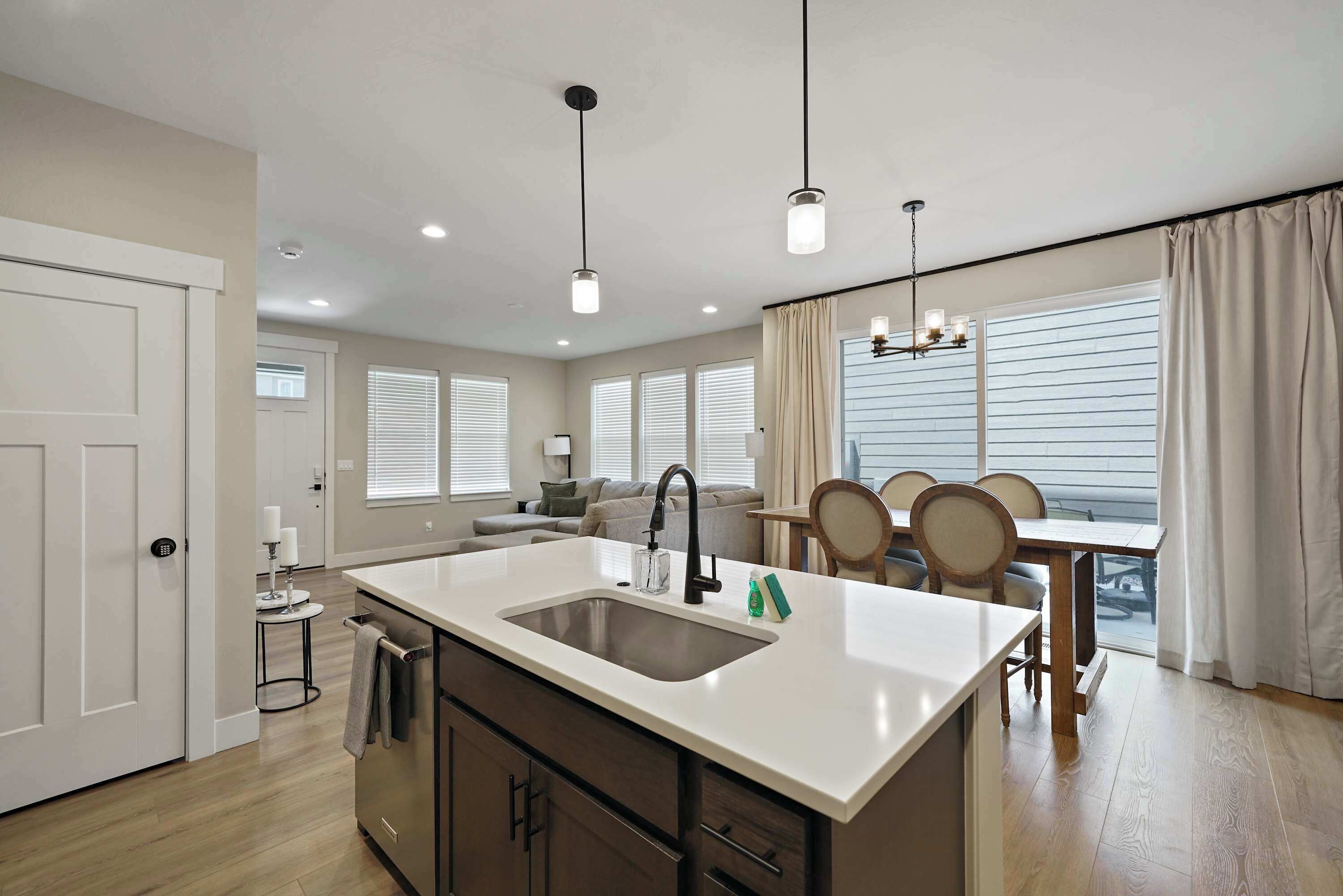 Una cocina moderna con una isla central, un comedor con candelabro y vistas al exterior.