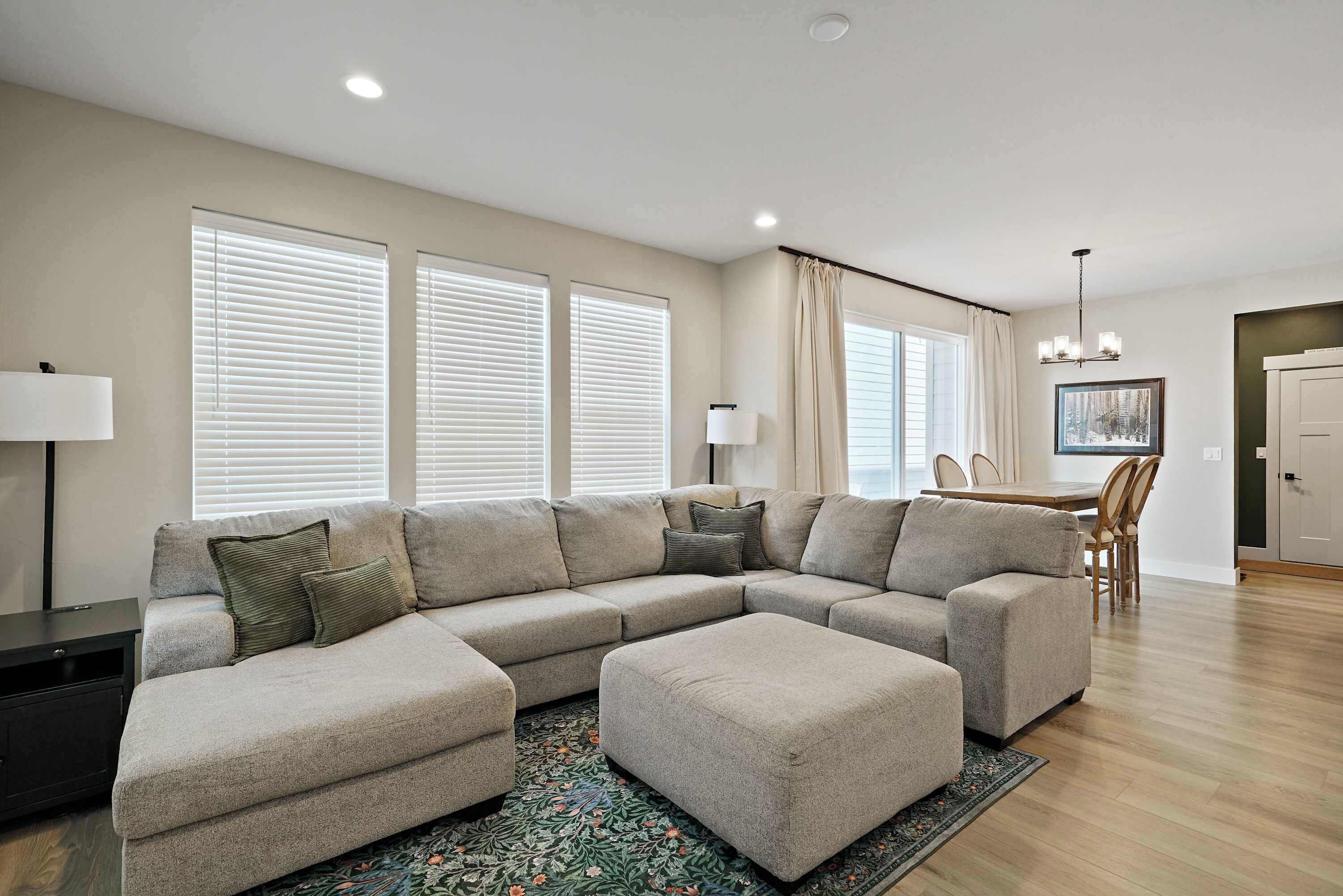 A modern living room with a sectional sofa, a dining area, and a chandelier.
