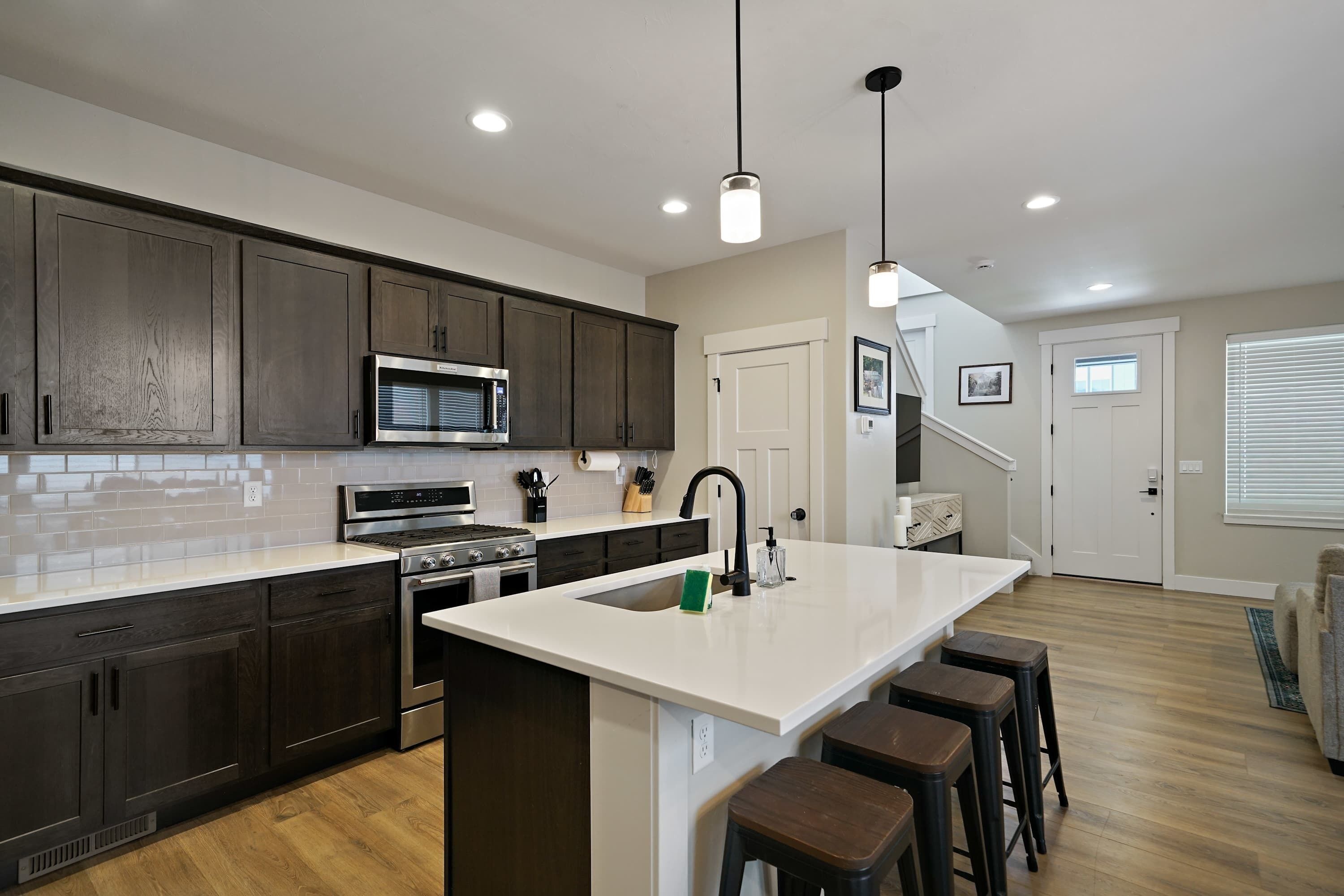 Una cocina moderna con armarios de madera oscura, electrodomésticos de acero inoxidable y una isla central con taburetes.