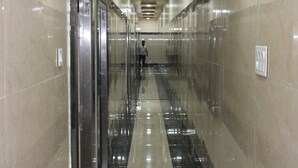 A corridor with reflective floors and walls, leading to an elevator. - Srivari Lodge (Aarkadu)