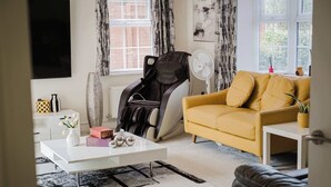 Un salon comprenant un canapé, un fauteuil massant, une table basse et un ventilateur.