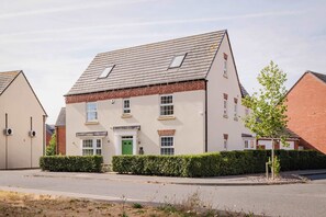 A two-story residential building with a pitched roof, multiple windows, and a green door. - Spacious 5-bed Home in Milton Keynes by Renzo, Driveway Parking, Close to M1 (Milton Keynes)