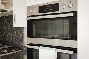 A kitchen with two stainless steel ovens, a digital clock, and a granite countertop. - Spacious 5-bed Home in Milton Keynes by Renzo, Driveway Parking, Close to M1 (Milton Keynes)
