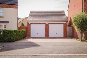 Eine Garage mit zwei weißen Türen, einem geneigten Dach und einem gepflasterten Auffahrt.