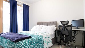 Una habitación de hotel con una cama, un escritorio con una computadora y una silla.