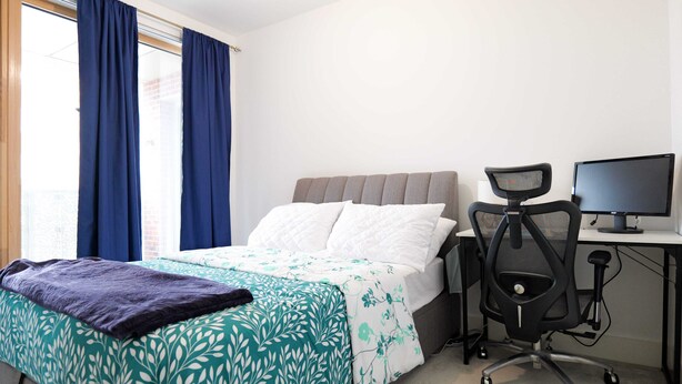 Una habitación de hotel con una cama, un escritorio con una computadora y una silla.