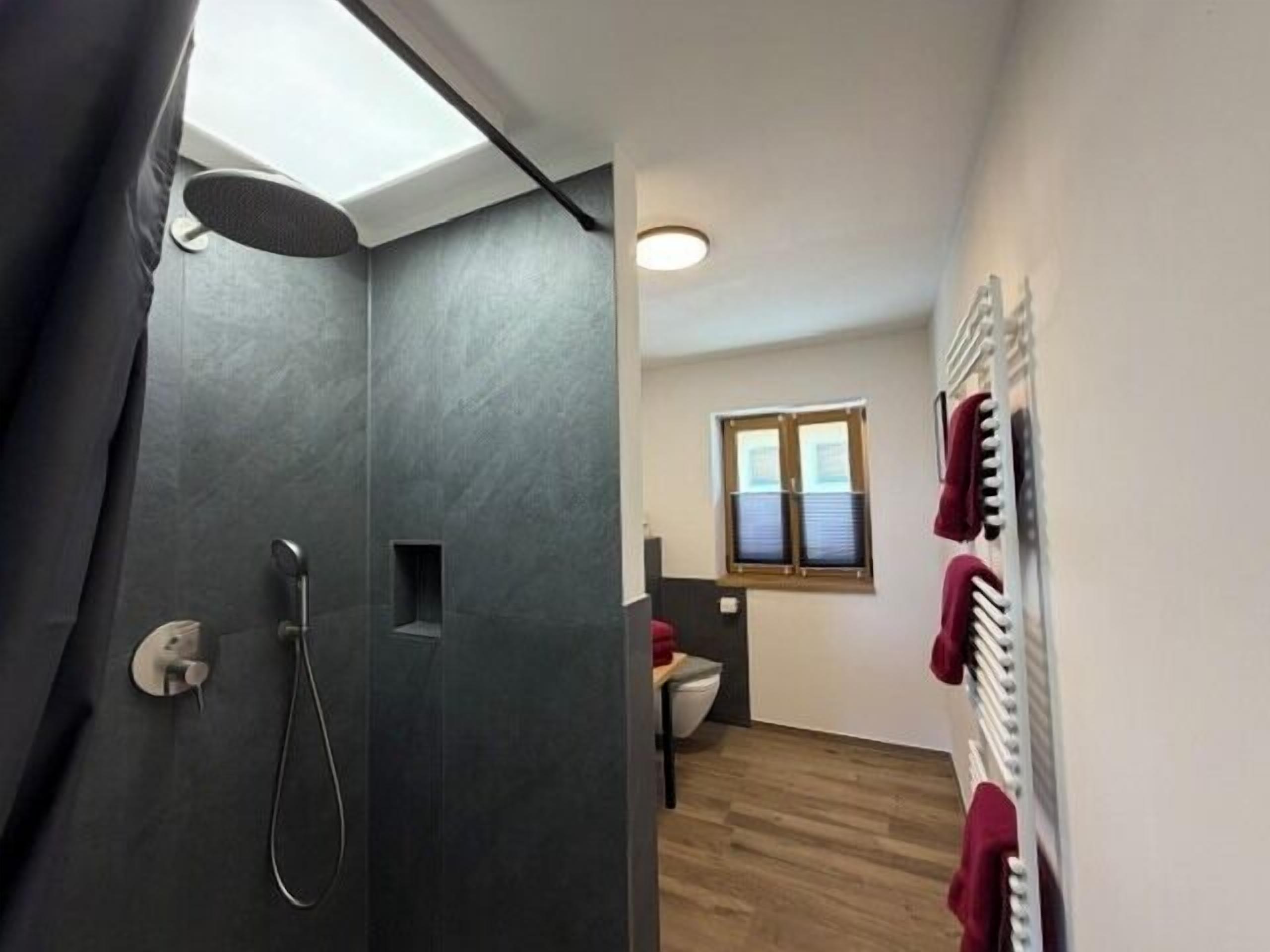 Ein modernes Badezimmer mit Dusche, Fenster und Handtuchhalter.
