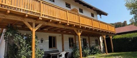 A two-story building with a wooden balcony and a covered outdoor seating area.