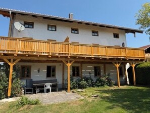 A two-story building with a balcony, a satellite dish, and a patio area with a table and chairs. - Edelweiß Vacation Rental, 68 square meters (Grabenstätt)