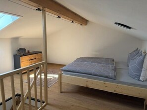A bedroom with a single bed, a wooden dresser, and a skylight. - Edelweiß Vacation Rental, 68 square meters (Grabenstätt)