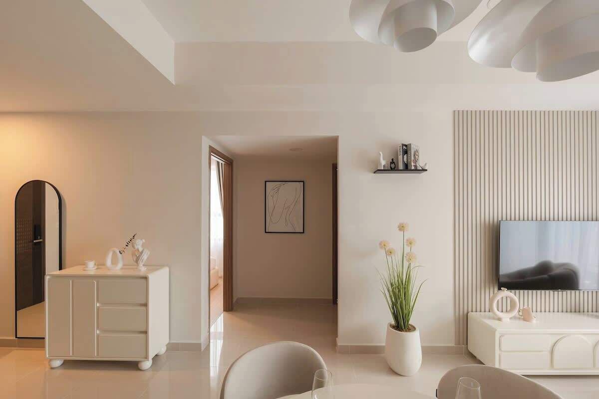Ein modernes Wohnzimmer mit Flachbildfernseher, weißem Sofa, Couchtisch, Schrank und einer Topfpflanze.