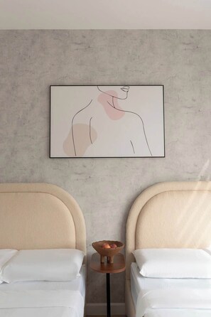 A hotel room with two beds, a small table with a bowl, and a wall-mounted abstract painting. - Corner 2BR/3Beds • River View • Walk to Bui Vien (Thành phố Hồ Chí Minh)