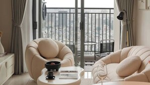 Una sala de estar moderna con un sofá, un sillón y una mesa de comedor con un cuenco de fruta.