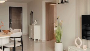 Una sala moderna con un sofá, una mesa de centro, un televisor y un comedor con sillas y una mesa.