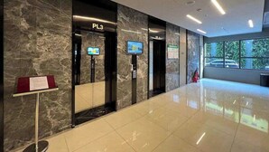 Un vestíbulo moderno con paredes de mármol, un mostrador de recepción y una pantalla informativa digital.