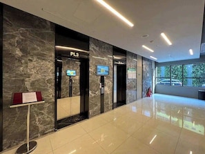 A modern lobby with marble walls, a reception desk, and a digital information screen. - Corner 2BR/3Beds • River View • Walk to Bui Vien (Thành phố Hồ Chí Minh)