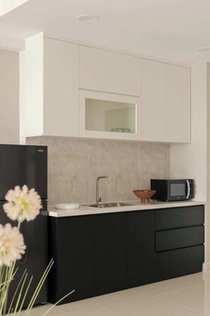 A modern kitchen with a black refrigerator, a microwave, and a sink. - Corner 2BR/3Beds • River View • Walk to Bui Vien (Thành phố Hồ Chí Minh)