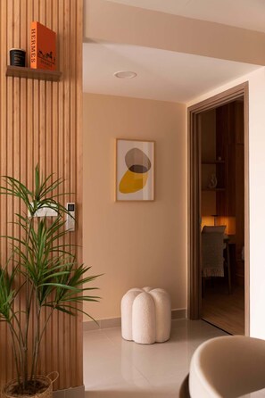 Ein modernes Interieur mit einer Holzpaneelausstattung, einem gerahmten abstrakten Kunstwerk, einer Topfpflanze und einem weißen Hocker.