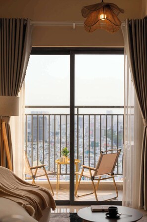 Ein Hotelzimmer mit einer großen Schiebeglastür, die auf einen Balkon mit Blick auf die Stadt führt.