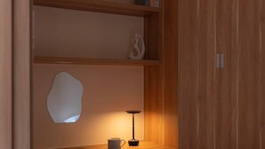 A compact bedroom with a wooden wardrobe, a desk with a chair, a bedside table, and a small bedside lamp. - High-Rise | 2Br+1Wc | Central | D1 | 1min BuiVien (Thành phố Hồ Chí Minh)