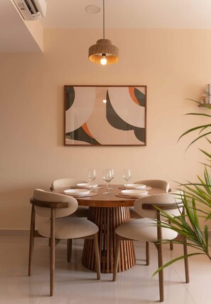 A dining area with a round wooden table, six chairs, and a hanging light fixture.
