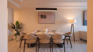 A modern dining area with a table set for four, surrounded by chairs, a potted plant, and a painting on the wall. - 3BR+2BA | 4 Beds | Sleeps 11 | Bitexco View | D1 (Thành phố Hồ Chí Minh)